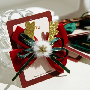 Close-up of velvet Christmas bow hair clip with gold reindeer antlers and snowflake