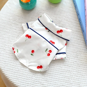 Close-up of silk-like pet pajamas with cherry print and navy blue piped edges