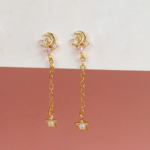 Close-up of gold tassel earrings with crescent moon, stars and pink zircon inlay