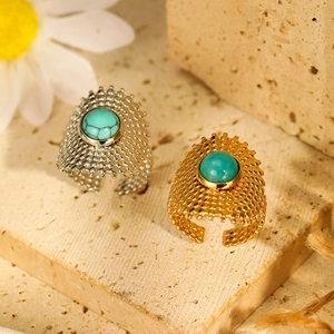 Detailed shot of gold and silver textured rings with turquoise stones on stone surface