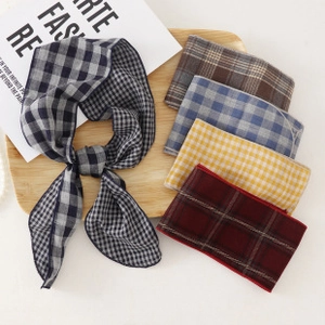 Flat lay of multiple checkered silk scarves in five colors on a wooden tray detail