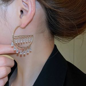 Detail view of gold earrings with cubic zirconia fringes shown on a model