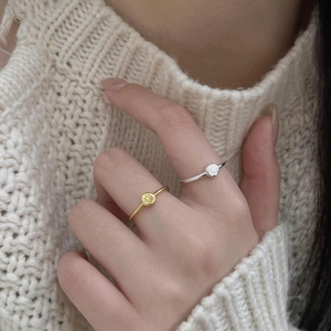 Close-up of gold and silver starburst rings worn by a model against a beige sweater