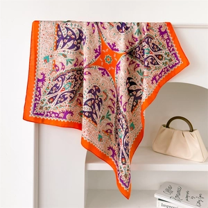 Detail of vintage paisley silk-like scarf with orange and purple drape on white shelf