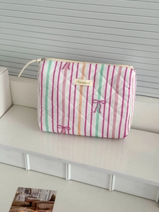 Quilted makeup bag with colorful vertical stripes and pink bow prints in a soft scene