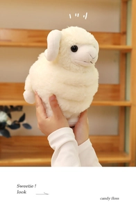 Close-up of soft white plush sheep doll with curved horns being held by hand