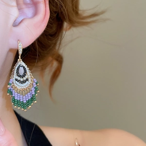 Detail of colorful beaded tassel earrings in bohemian style worn by a female model