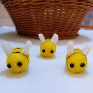 Three handmade wool felt bees with yellow bodies and white wings for DIY craft projects