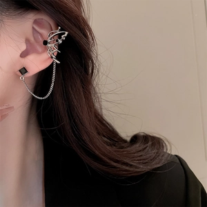 Detail view of silver butterfly ear cuff with black gemstone and tassel chain link