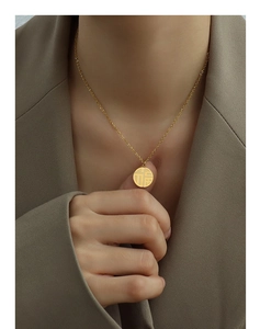 Close-up of gold Fu character pendant necklace on a model with elegant lighting