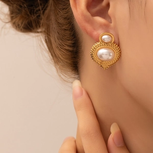 Close-up of vintage gold double pearl earrings with beaded edge on female ear
