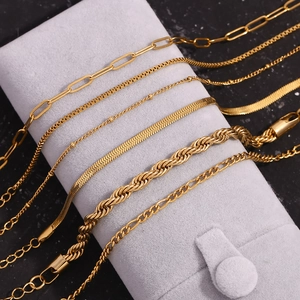 Close-up of assorted 18K gold plated stainless steel chains on a grey velvet pouch