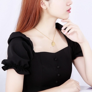 Detailed close-up of a gold Aquarius zodiac pendant necklace worn by a fashion model