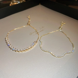 Close-up of adjustable gold wave bracelets with brilliant cubic zirconia in warm lighting