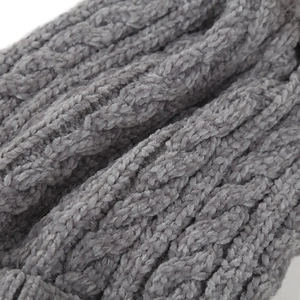 Close-up of grey cable knit texture and soft material on winter pom pom beanie