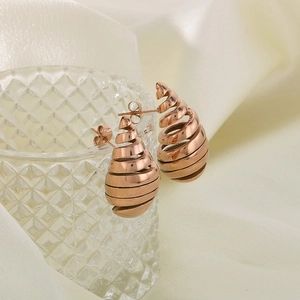 Macro shot of rose gold spiral taper earrings hanging on a luxury glass display