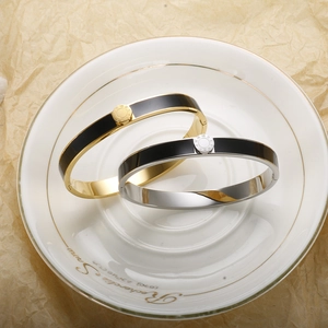 Macro detail of gold and silver stainless steel bangles with Roman numerals and black enamel