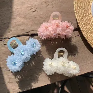 Close-up of floral hair claws in pastel pink, blue, and cream on a vintage wood background