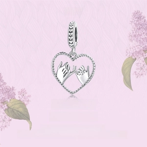 Macro detail of S925 sterling silver heart charm with pink floral romantic background