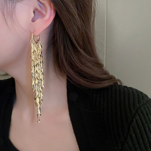 Macro shot of gold leaf tassel earrings showing layered metal scales and flexible fringe