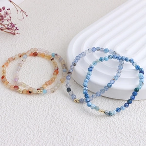 Close-up of elegant beaded pearl bracelets in blue and orange on a white texture tray