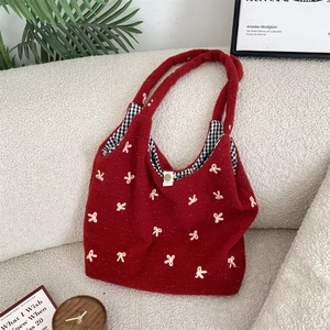 Red plush tote bag with white embroidered bows and plaid lining in home setting
