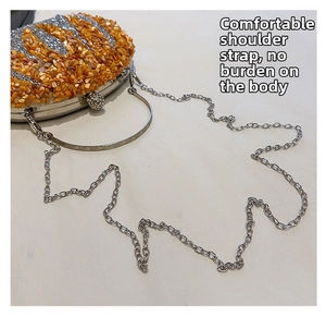 Detail of evening clutch featuring orange shell fragments, silver glitter, and metal chain