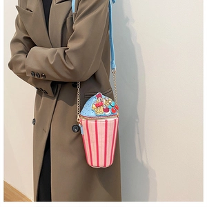 Detail of pink and red striped ice cream cone crossbody bag with cherry top on model