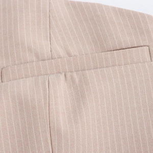 Close-up of beige pinstripe fabric texture showing a welt pocket and detailed stitching