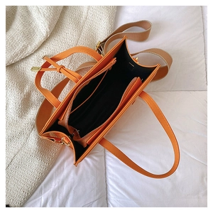 Interior view of orange PU tote bag showing black lining with central zip compartment
