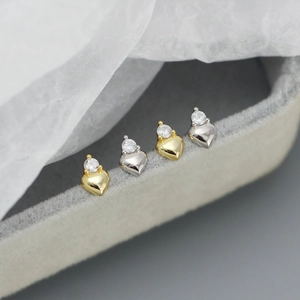 Macro view of gold and silver heart stud earrings with sparkling round zirconia accents