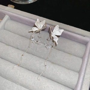 Close-up of silver butterfly tassel earrings with crystal beads in a velvet tray