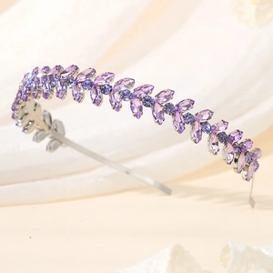 Detail of leaf-shaped rhinestone headband with purple crystals on a soft fabric backdrop