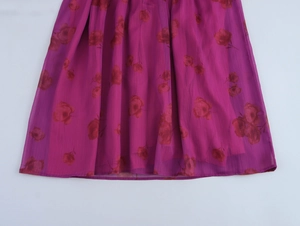 Détail d'une jupe en mousseline fleurie violette avec roses rouges et ourlet plissé