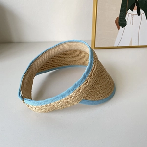 Détail du tressage en raphia naturel et bordure bleue du chapeau de soleil sur bureau