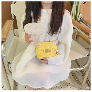 Cute yellow girl shoulder bag with pearl handle and cartoon charms shown with model