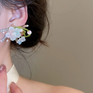 Primer plano de pendientes de botón de flores de cristal con aguja de plata
