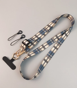 Detail of blue and grey plaid fabric phone strap with gold metal buckle and black patch