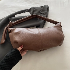 Modern dark brown pebble leather croissant shoulder bag styled on a grey blazer suit