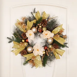 Luminous Christmas wreath with golden bows, pine cones, and white flowers on a white door
