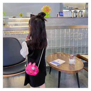 Rear view of a child wearing a rose red rabbit silicone crossbody bag with white strap
