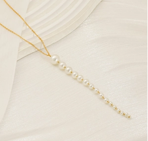 Détail d'un collier doré élégant avec une rangée verticale de perles blanches graduées