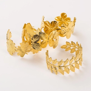 Macro shot of three gold textured open cuffs featuring butterfly and floral engravings
