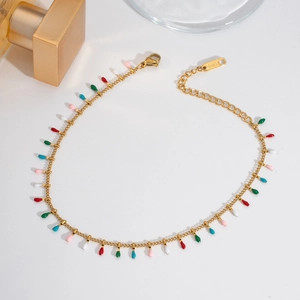 Detail of gold layered anklet featuring colorful teardrop enamel charms in a neat flat lay