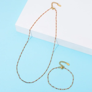 Detail of gold stainless steel jewelry set with red enamel beads and lobster clasp