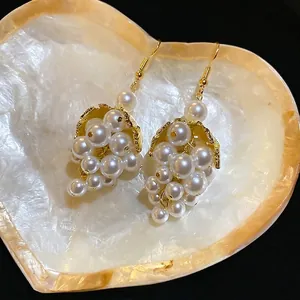 French vintage grape cluster pearl drop earrings with gold leaf accents on a shell tray