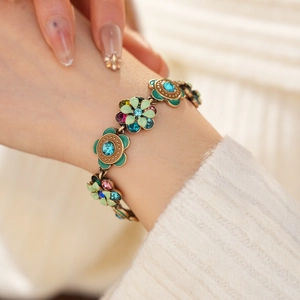 Close-up of vintage flower bracelet with colorful crystals and green enamel details
