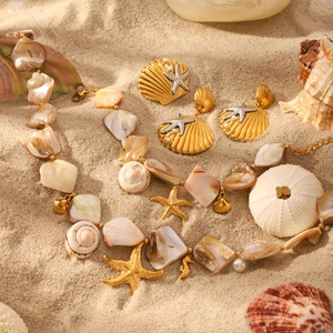 Golden starfish and shell jewelry set with pearls on sand, beach theme necklace and earrings