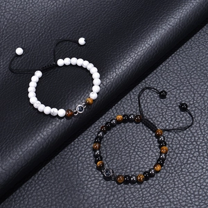 Detail of beaded bracelets with 100 languages projection pendant on black leather surface