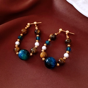 Détail des boucles d'oreilles en perles et pierres sur un tissu en soie foncée